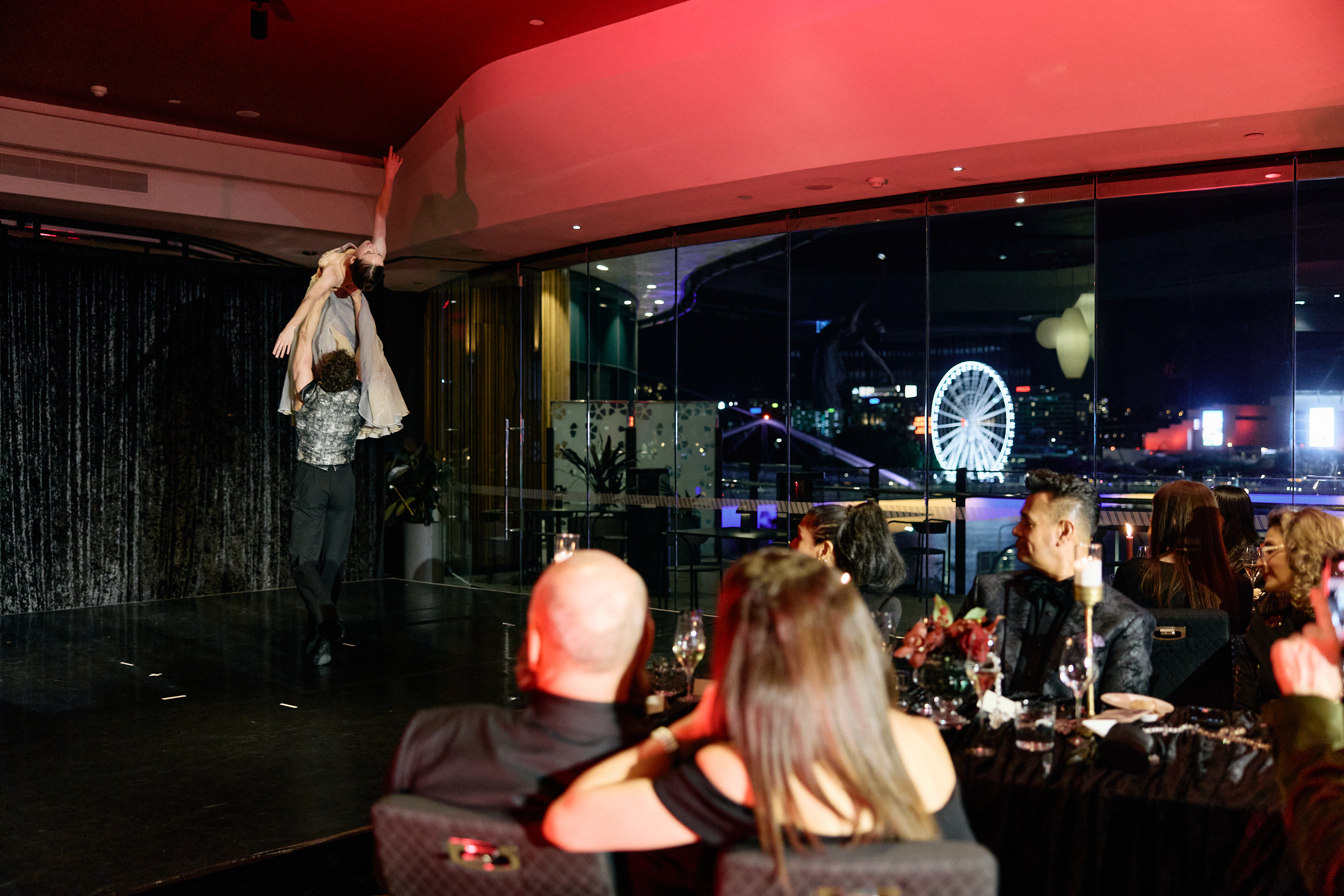 Principal Artist Lucy Green and First Company Artist Joshua Ostermann perform a live Pas de Deux excerpt, with the Wheel of Brisbane visible through the window.