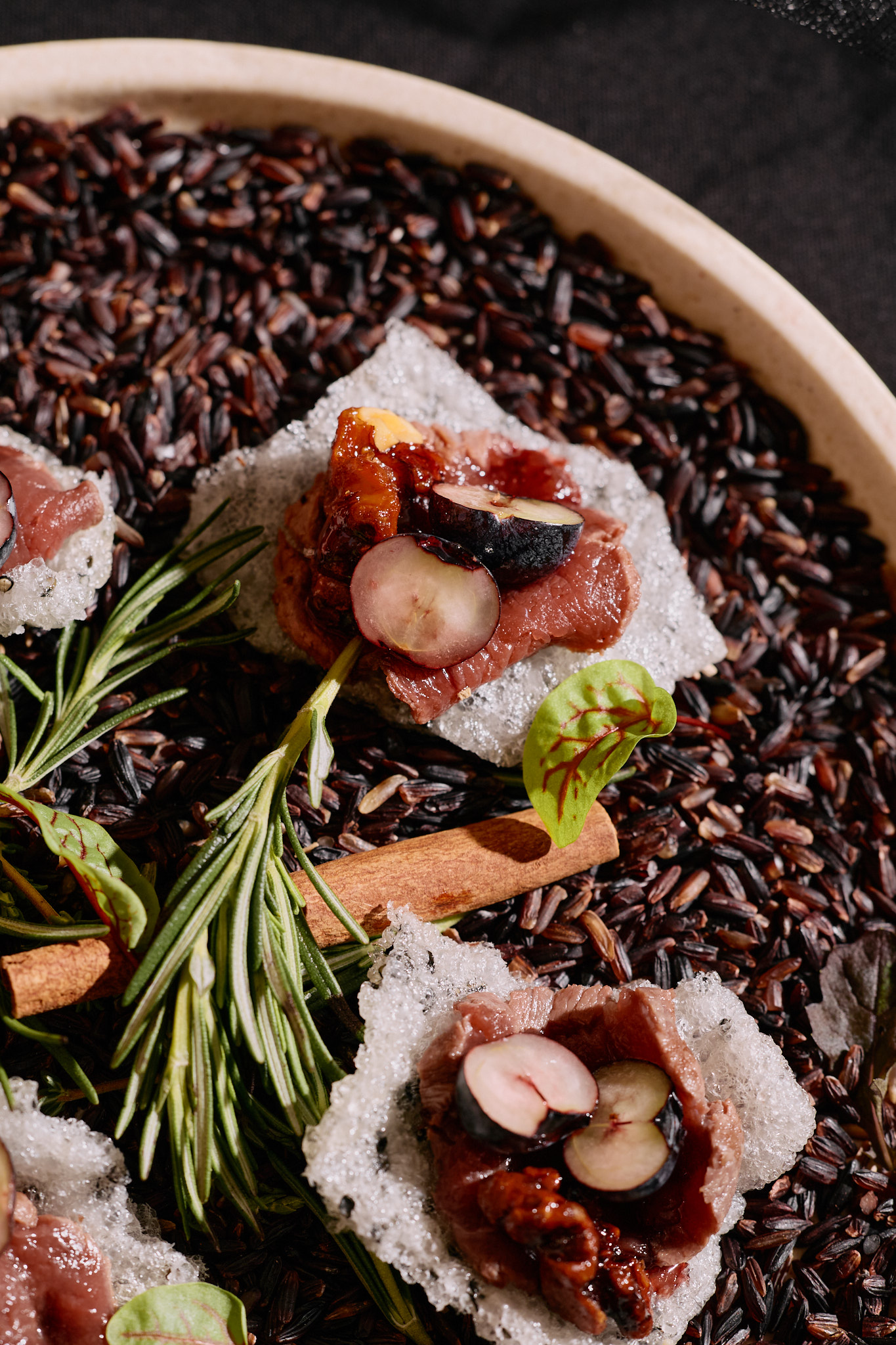 Smoked venison with pickled blueberries, candied walnuts and red wine jam, plated over black rice.
